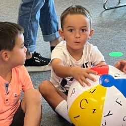 A kindergartner holding a colorful inflatable ball.